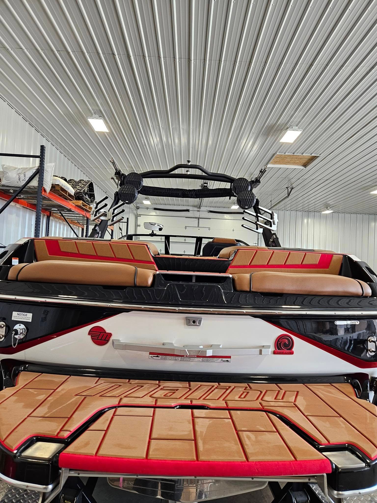 A view from the stern of a boat featuring tan and red cushioned seating, a wooden swim platform, and a metal tower.