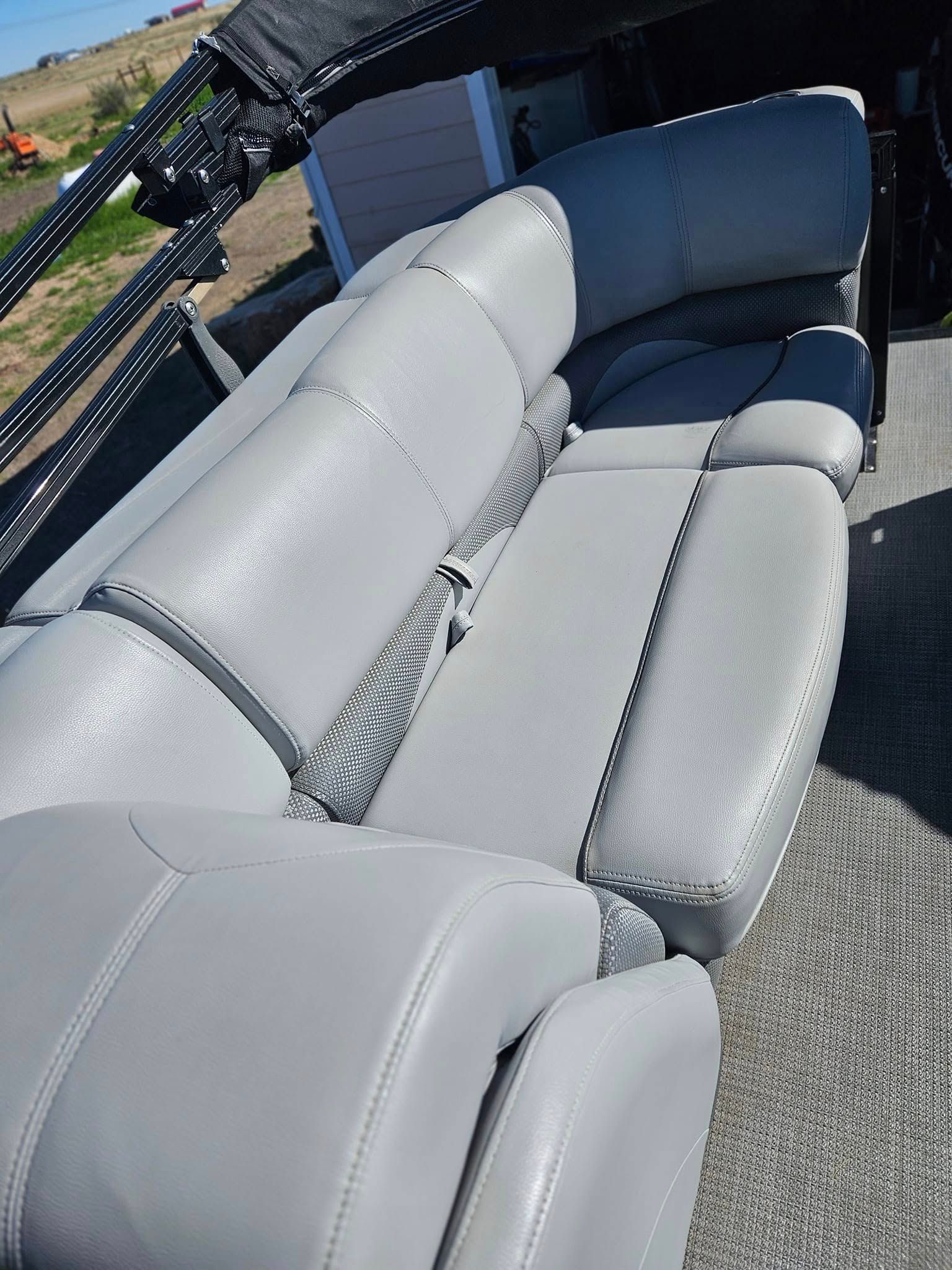 Light gray marine-grade vinyl bench seating on a boat, featuring stitched panels and a dark gray accent corner.