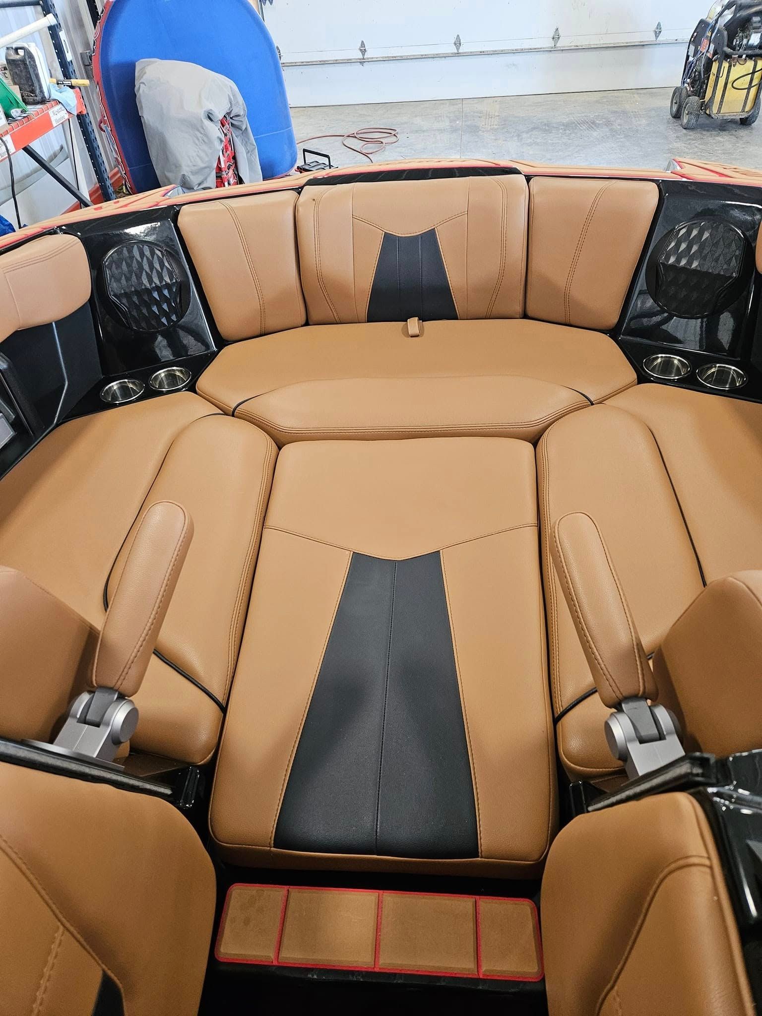 Custom tan and black leather boat interior seating with integrated speakers and fold-down armrests.