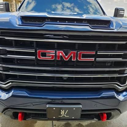 Front-facing view of a dark blue GMC truck, featuring a chrome grille, a prominent red GMC emblem, and red tow hooks.