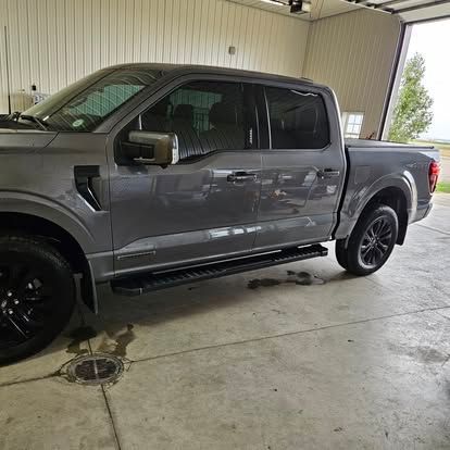 A gray Ford F-150 crew cab pickup truck parked inside a bright, clean garage with a concrete floor.