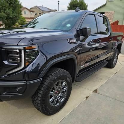 A dark blue GMC Sierra AT4 pickup truck parked on a residential concrete driveway.