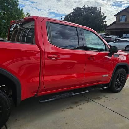 A vibrant red pickup truck parked on a concrete driveway in front of a house.
