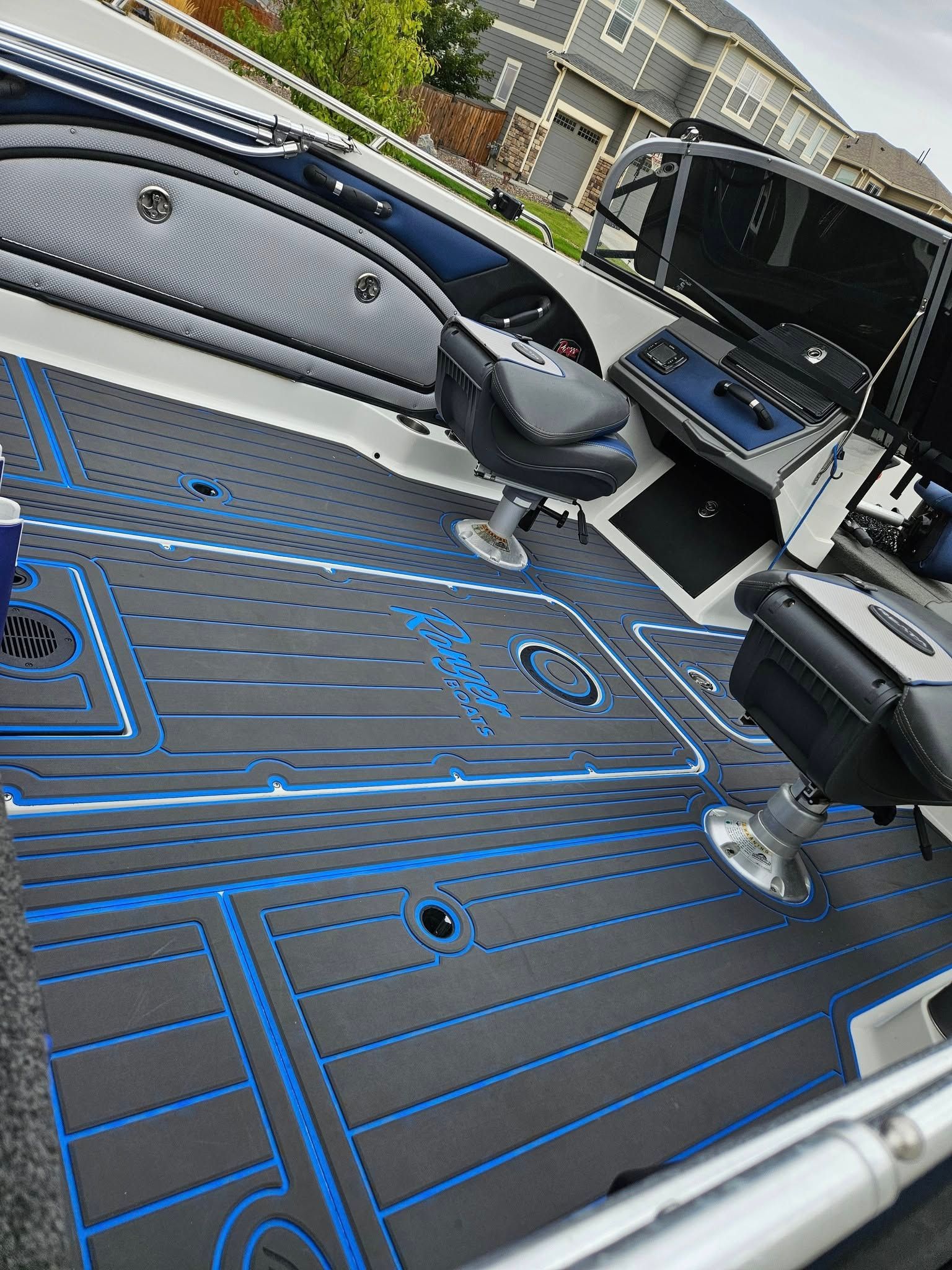 Boat deck with dark gray non-slip foam flooring featuring bright blue accent lines and a logo, seen from a high angle.