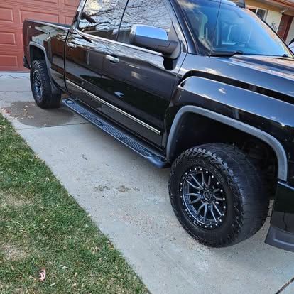 A black pickup truck parked on a concrete driveway in front of a red garage door.