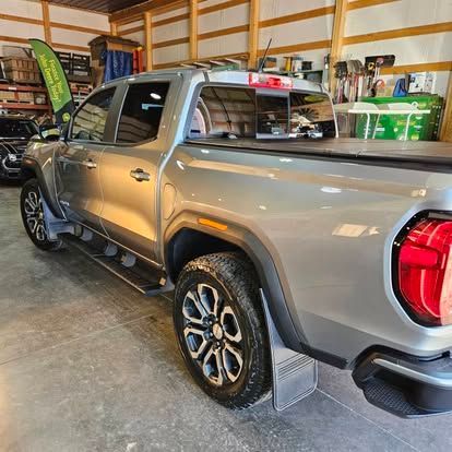 A gray pickup truck parked inside a garage, viewed from the rear passenger side.