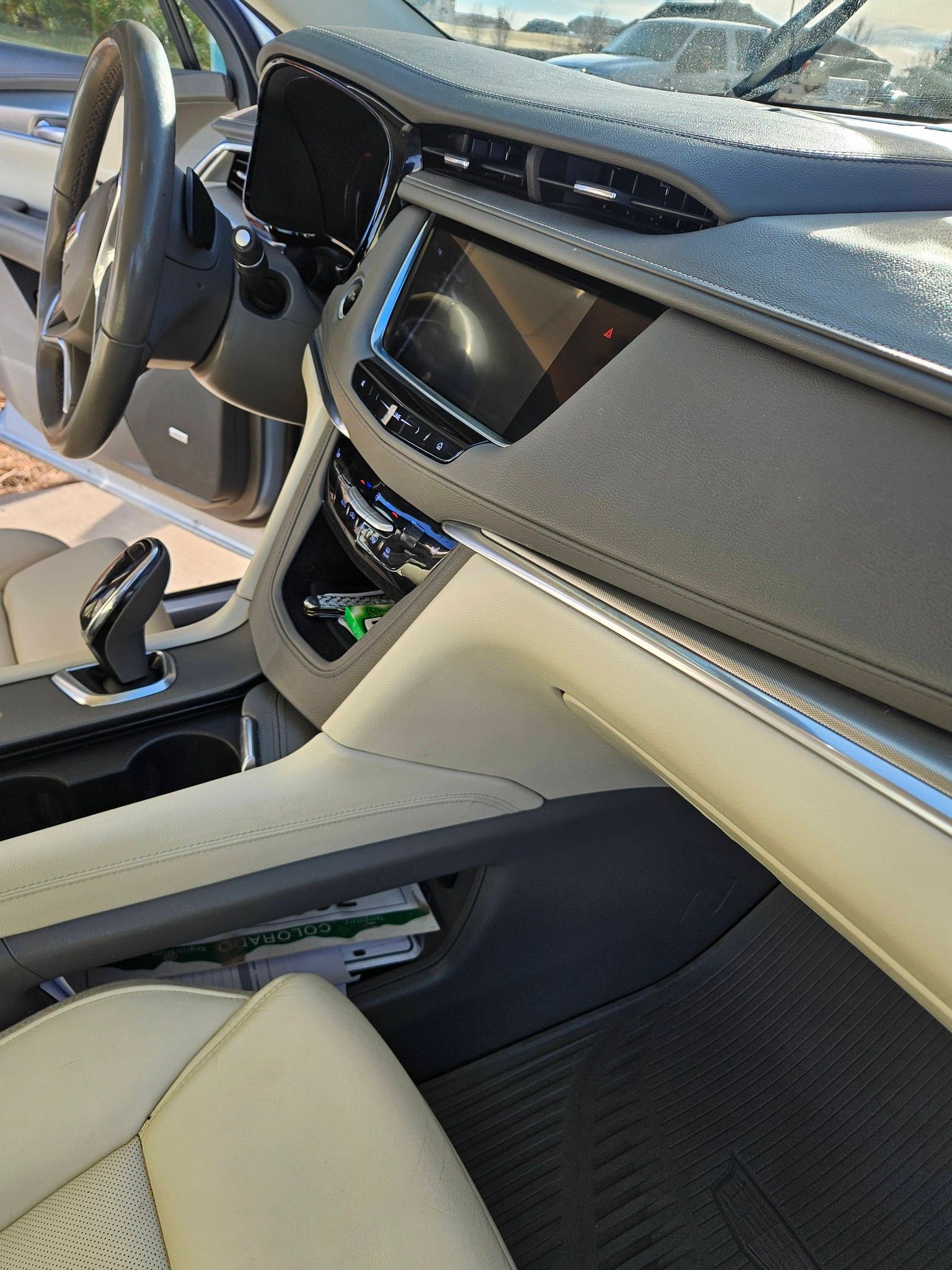 Interior view of a vehicle dashboard featuring a beige leather console, steering wheel, and black digital display.