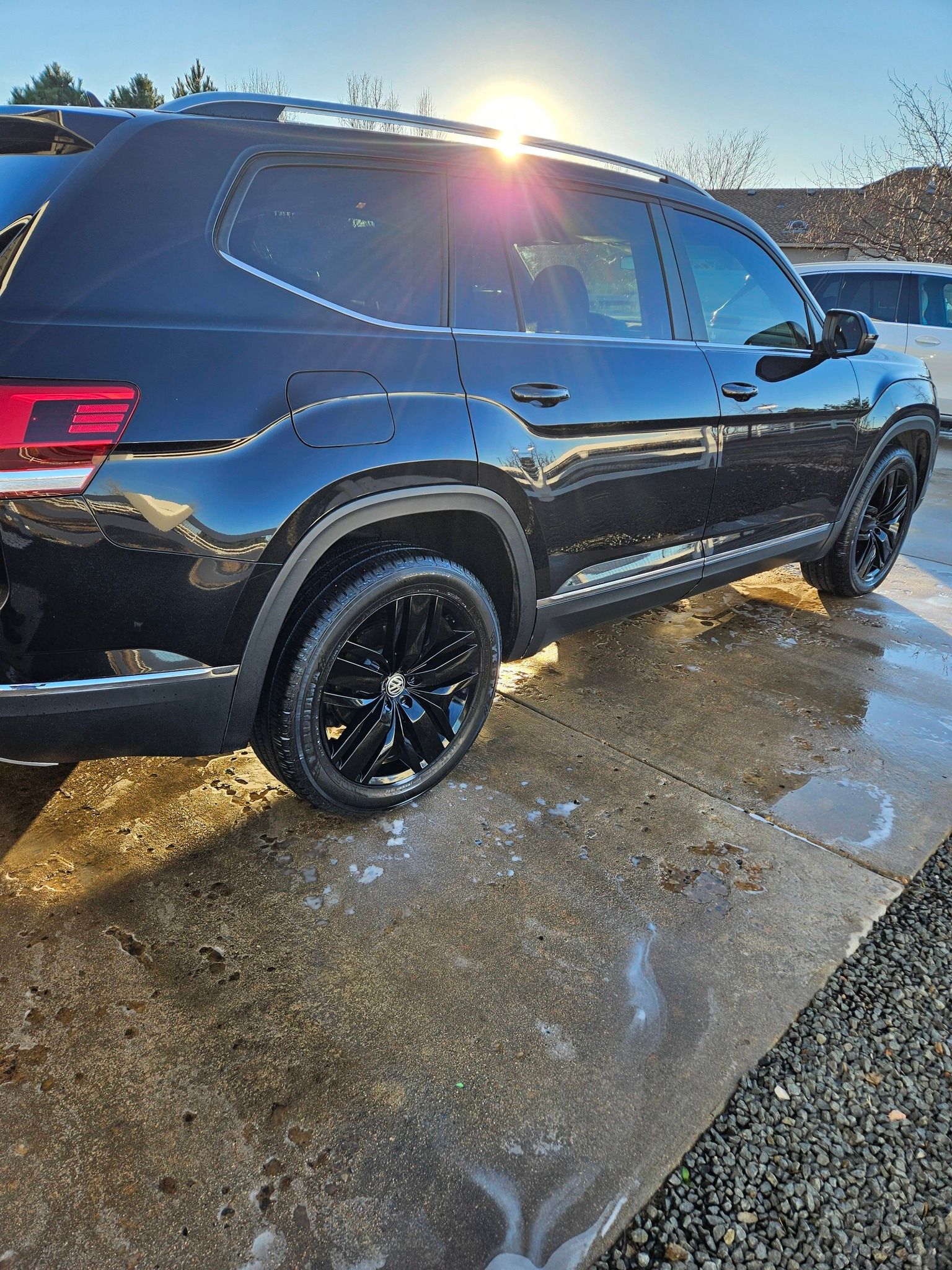 A black SUV parked on a wet concrete surface under bright sunlight.