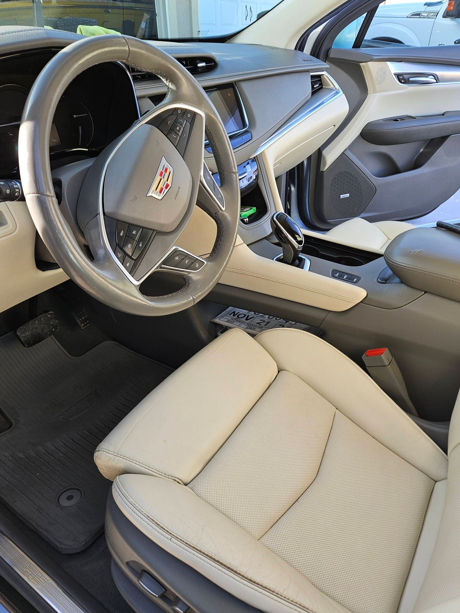 Interior of a Cadillac with beige perforated leather seats, a leather-wrapped steering wheel, and a center console.