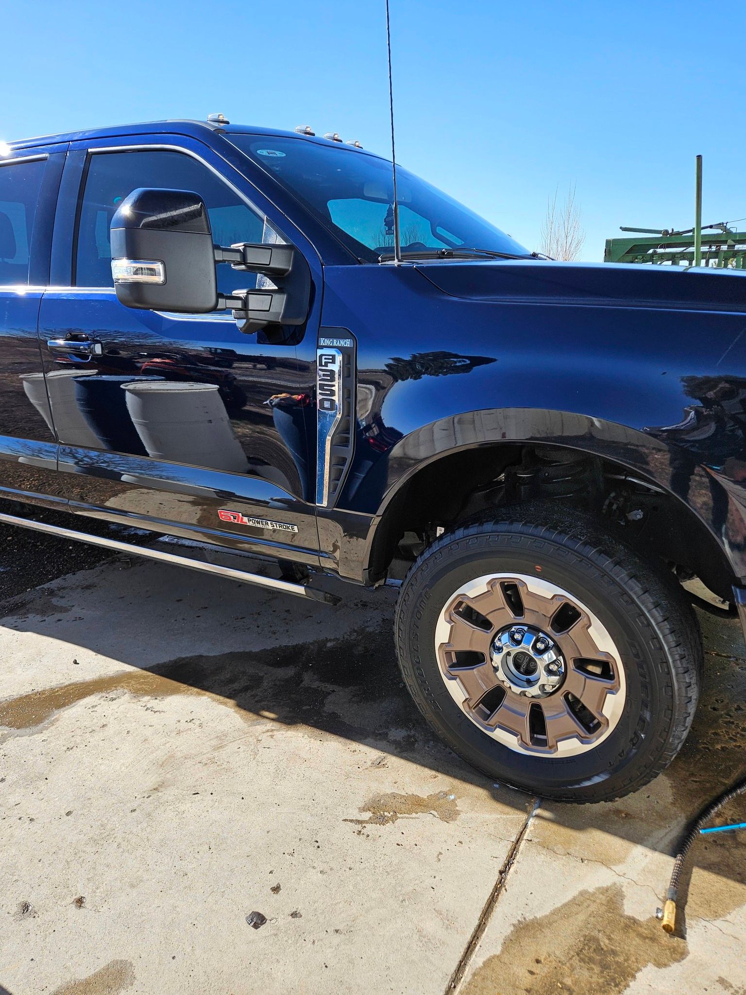 A dark blue Ford Super Duty pickup truck parked on a concrete surface on a sunny day.