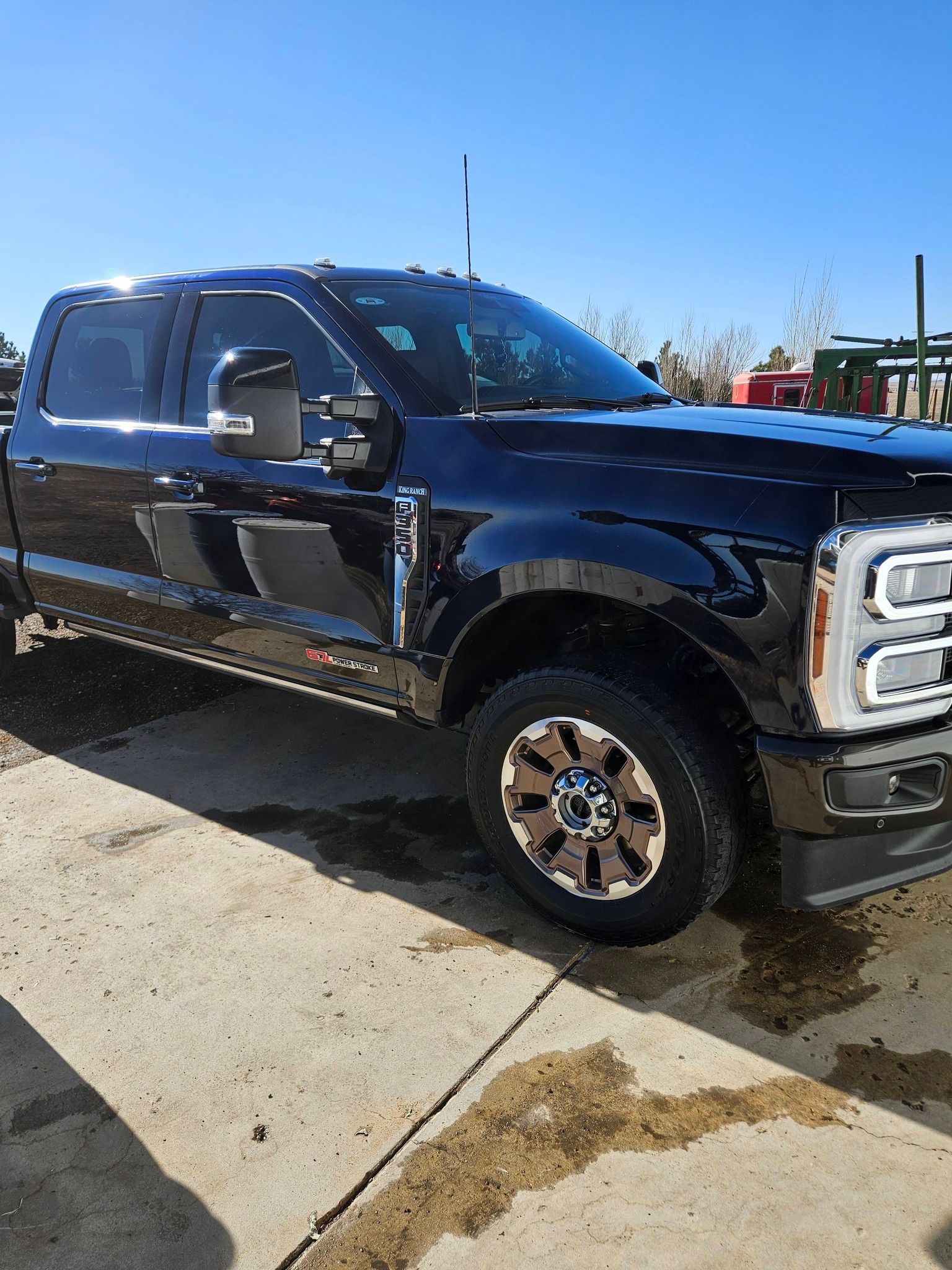 A black Ford Super Duty pickup truck parked on a concrete surface under a clear blue sky.