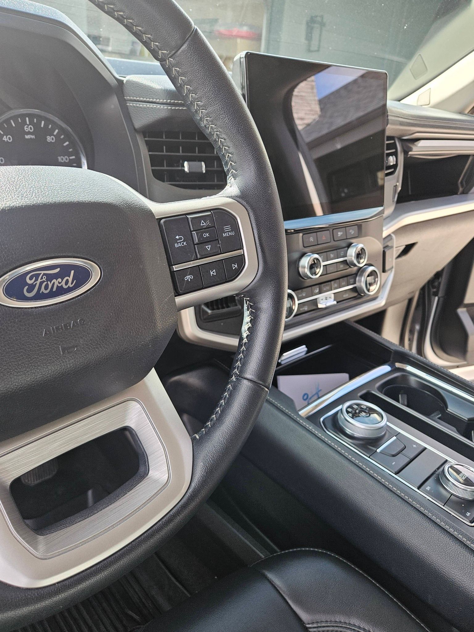 Driver's perspective of a Ford vehicle interior showing the steering wheel, dashboard, and center console touchscreen.