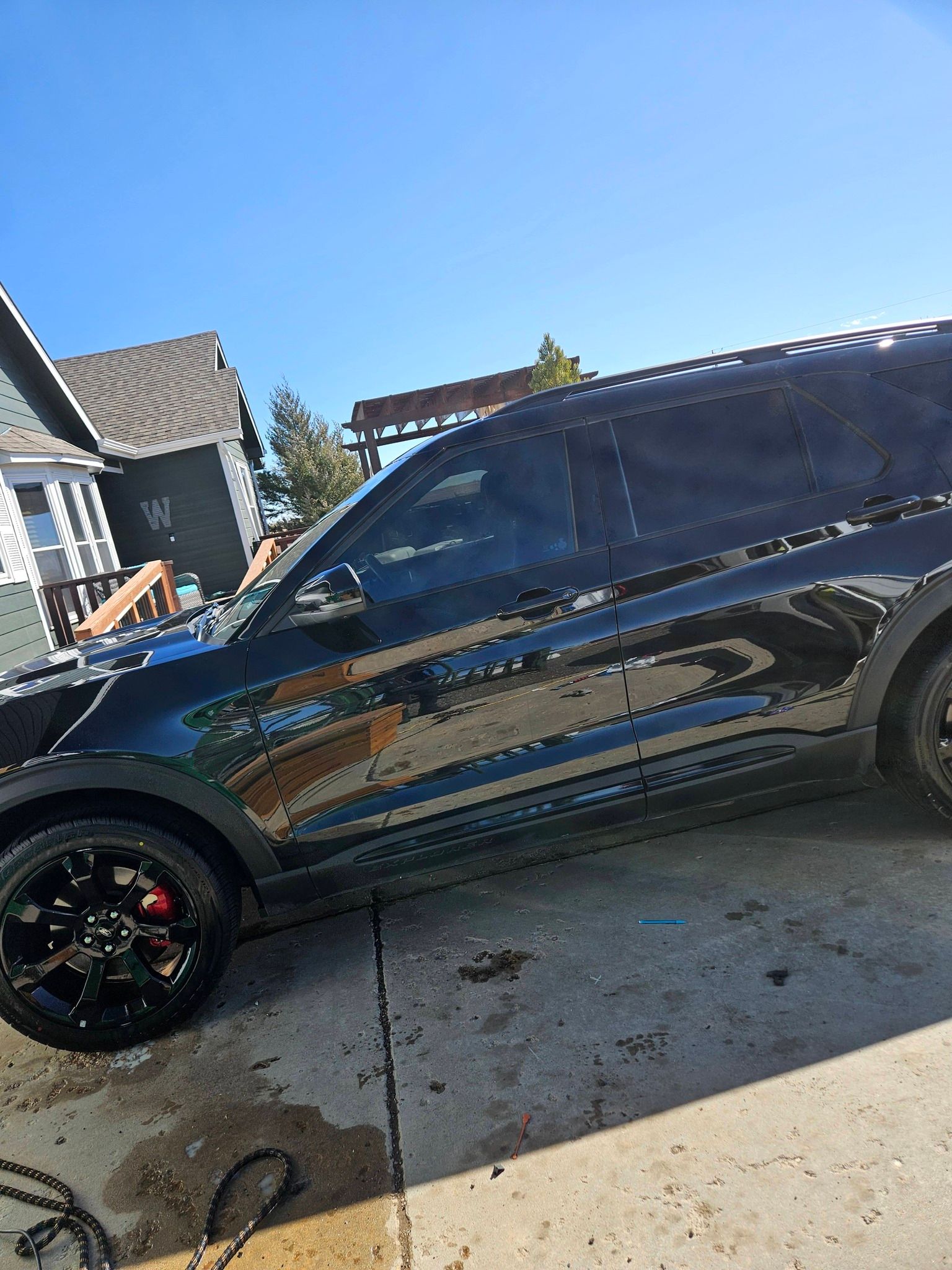 A side view of a black SUV parked on a concrete driveway during the day.