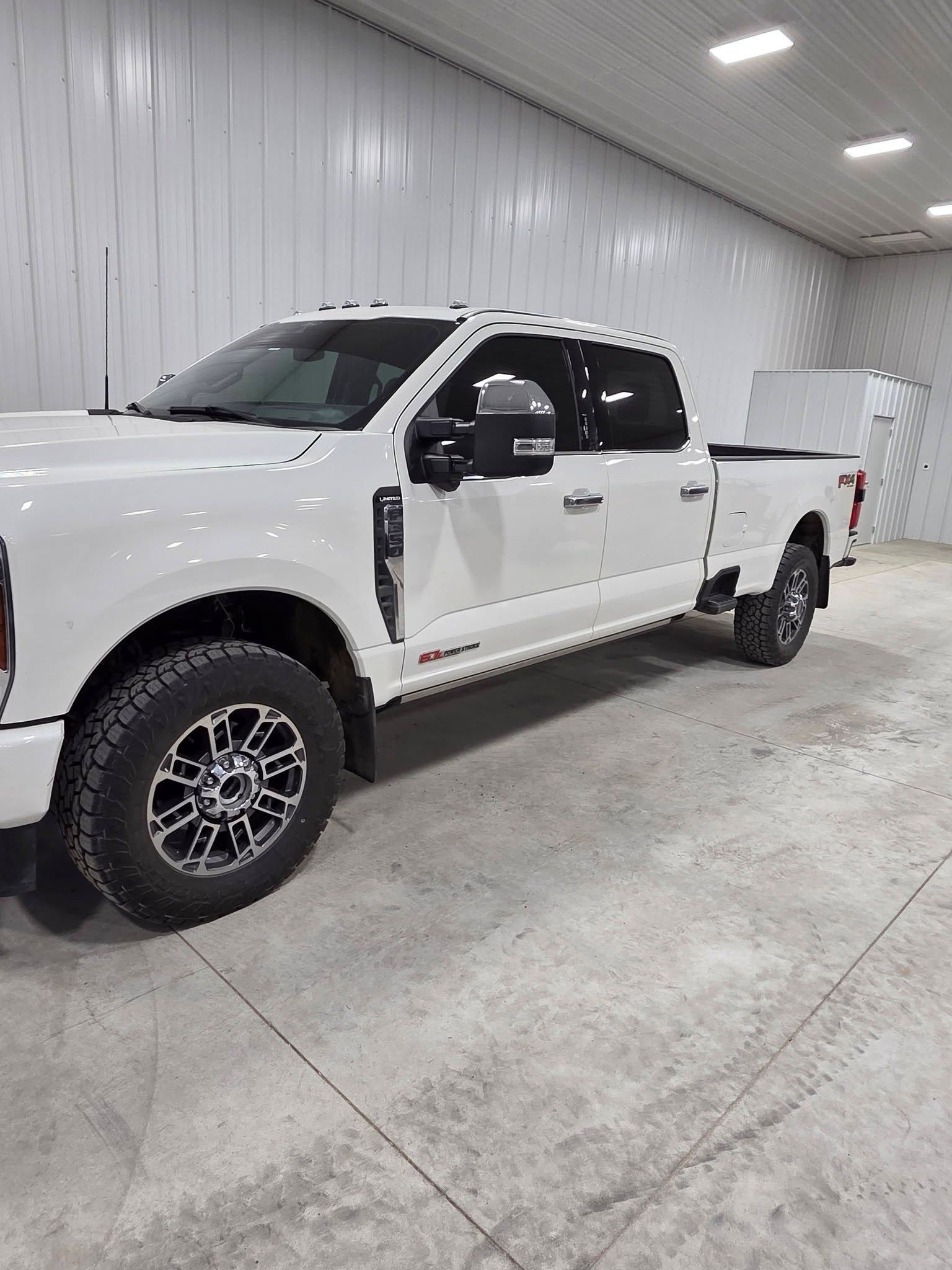 A white Ford F-Series crew cab pickup truck parked inside a well-lit industrial garage.