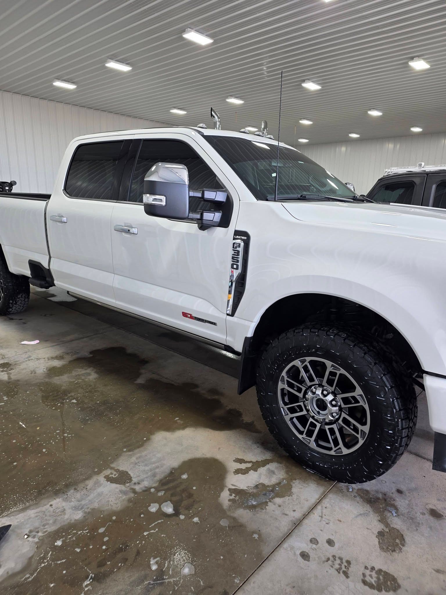 A white Ford F-Series pickup truck parked inside a bright, industrial building with a corrugated metal ceiling.