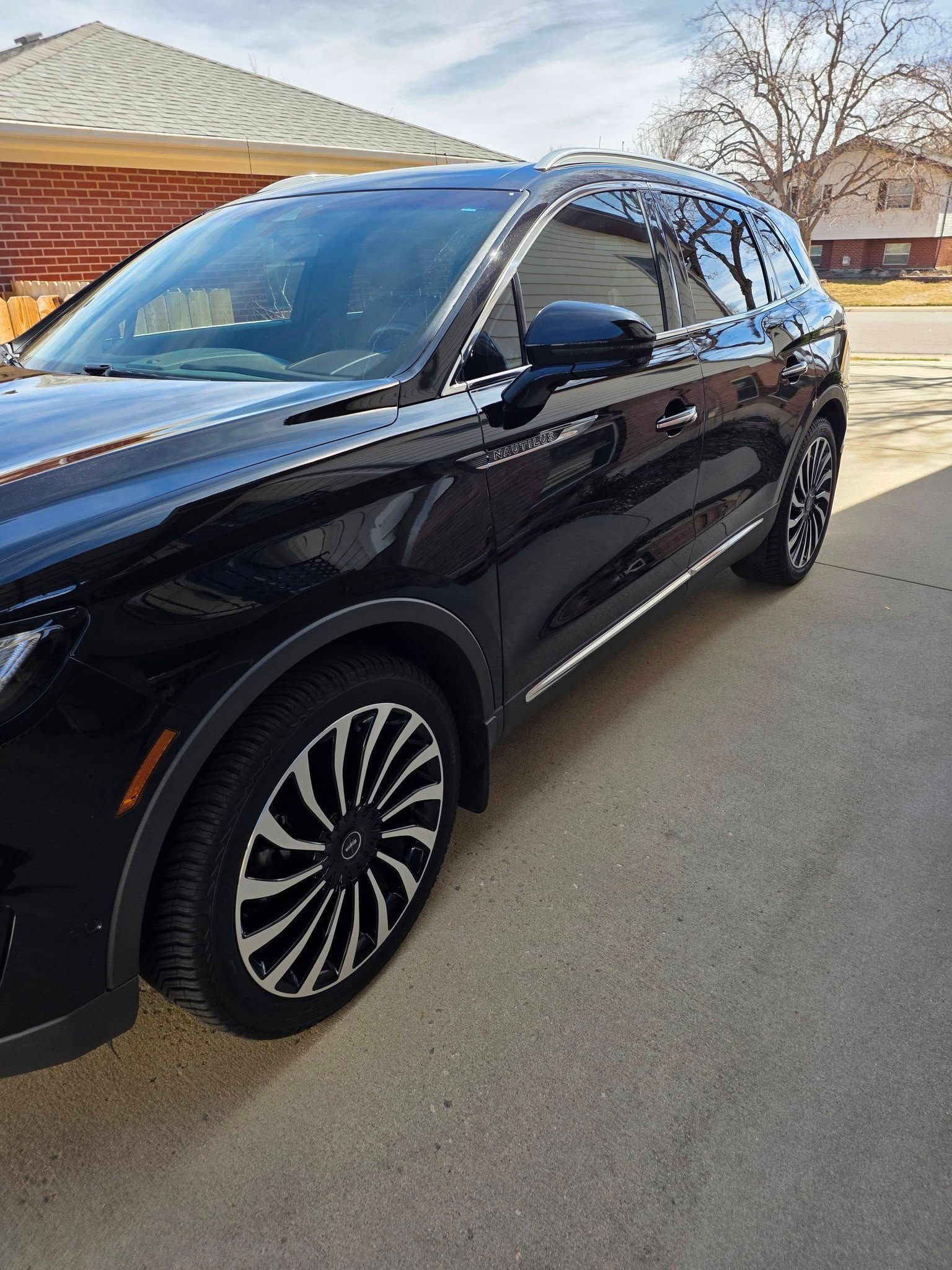 A black SUV parked on a concrete driveway in a residential area on a sunny day.
