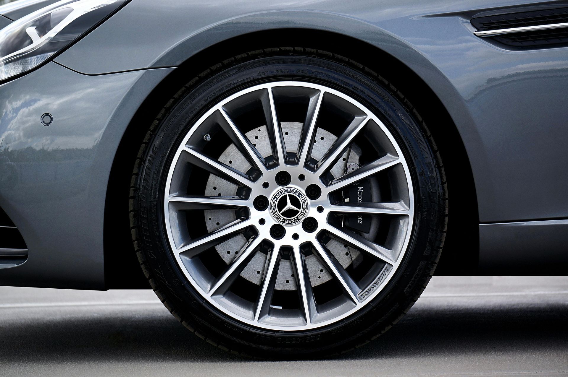 Close-up of a dark grey Mercedes-Benz car front wheel with a silver multi-spoke rim and a visible brake rotor.