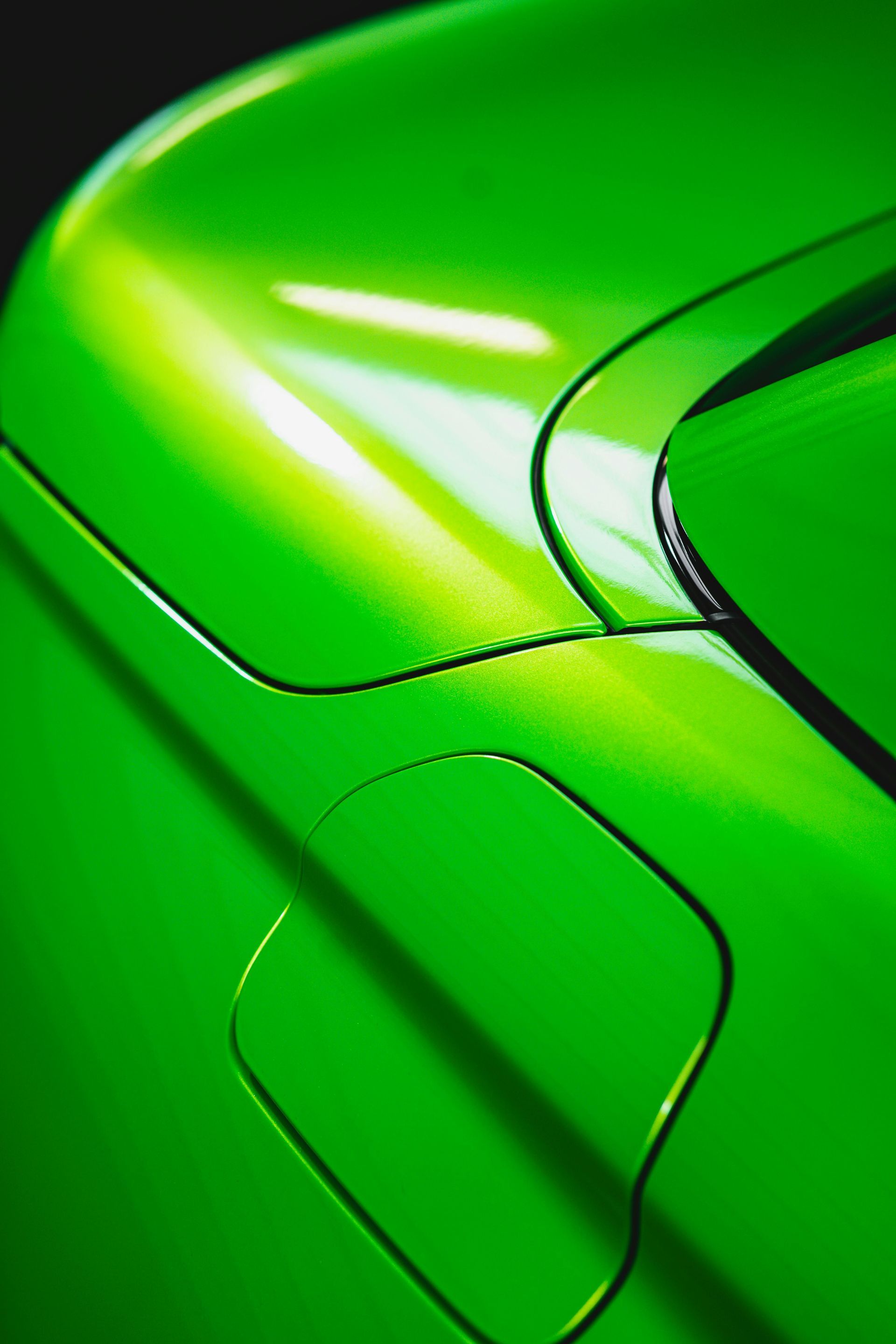 Close-up of a bright green carโs exterior, focusing on the fuel filler door panel and adjacent body lines.