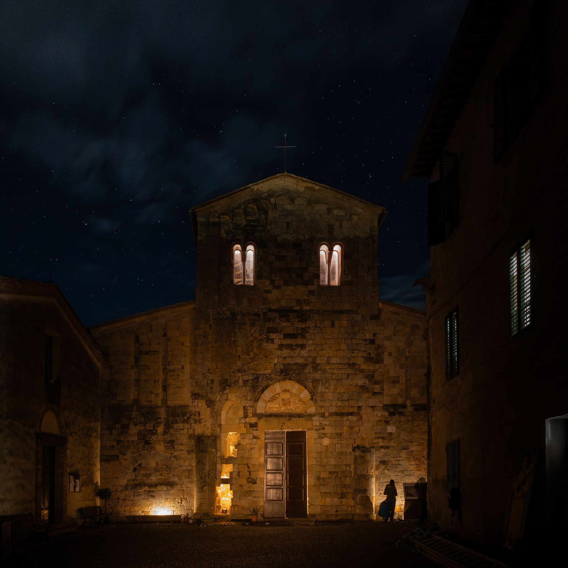 Historic stone building in Tuscany Italy, illuminated under a starry night sky, highlighting its architectural details