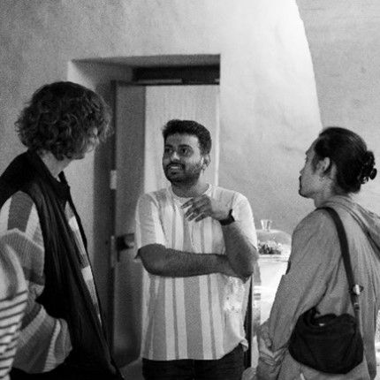 A group of people engaged in a discussion indoors, with one person gesturing while speaking.