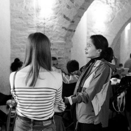Two people conversing in a dimly lit room with arched ceilings, likely discussing dark sky conservation