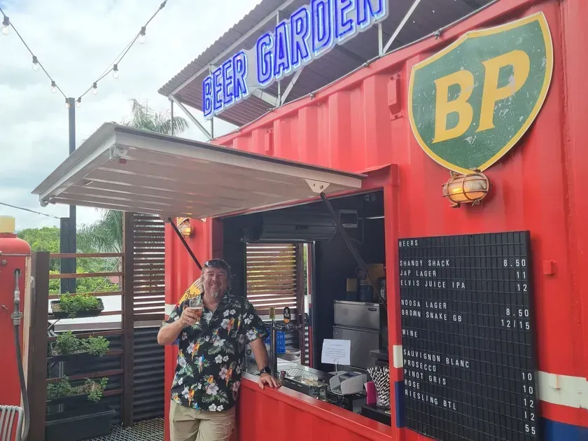 A man is standing in front of a red bp truck.