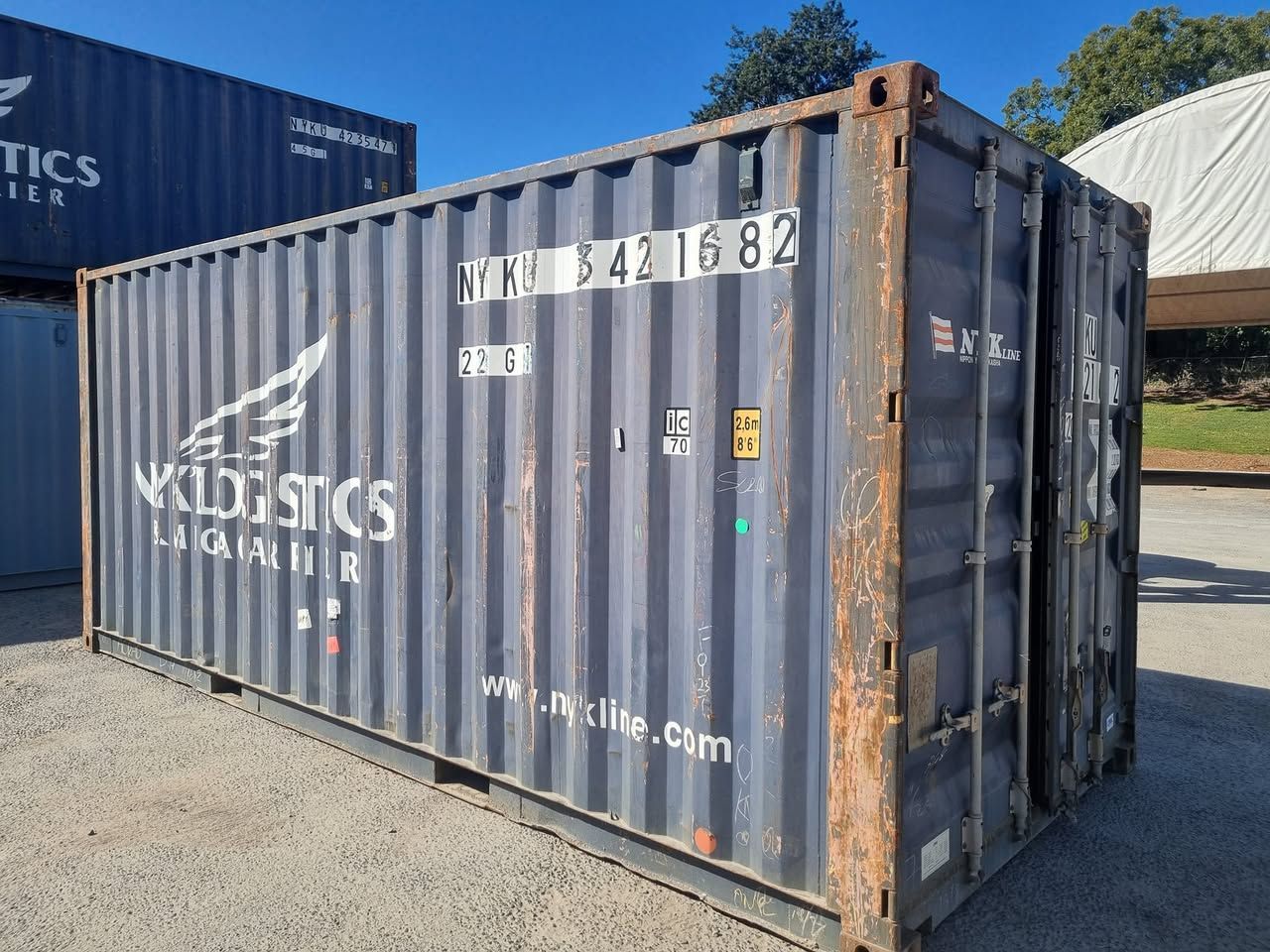 A shipping container with the word logistics on it is sitting in a parking lot.