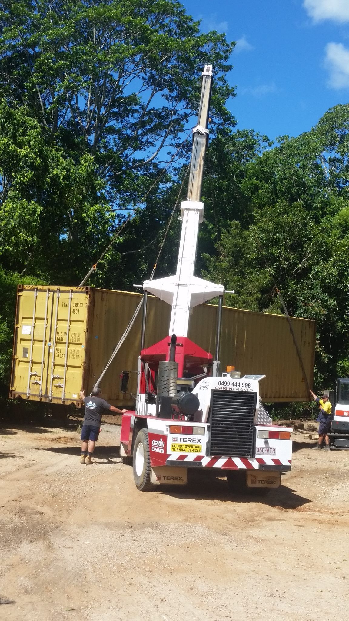A truck with a crane attached to it is parked in a dirt lot.