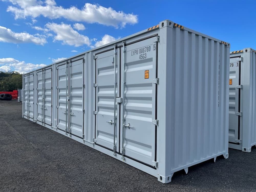 Row of White Shipping Containers on an Outdoor Lot Under a Bright Blue Sky With Scattered Clouds