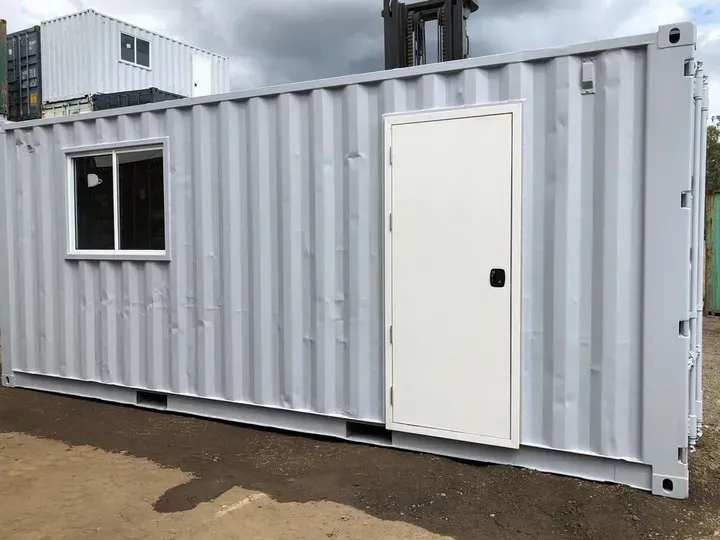 A gray shipping container with a white door and window.