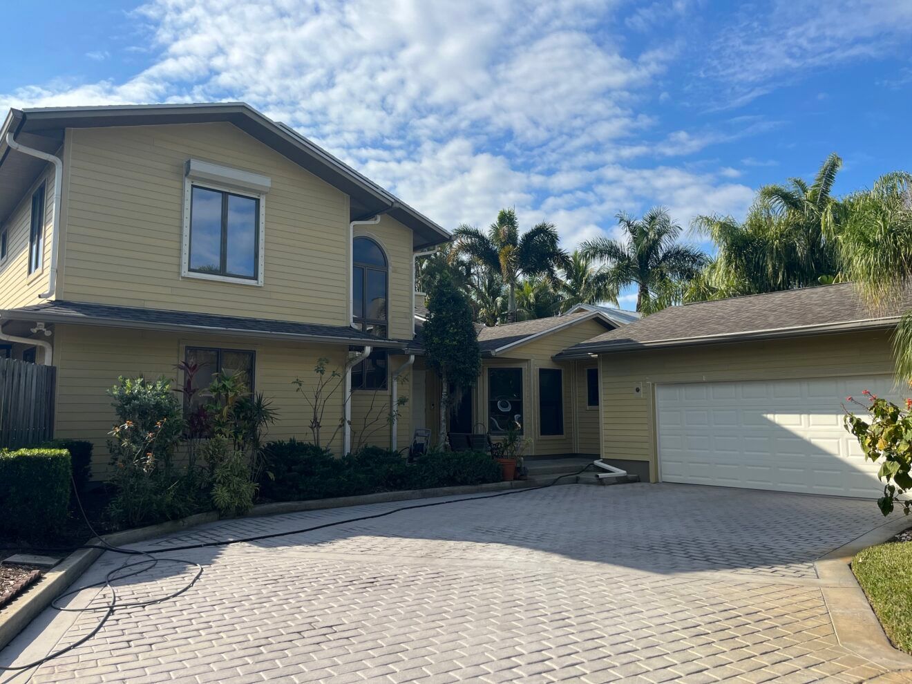A large yellow house with a white garage door and a driveway.