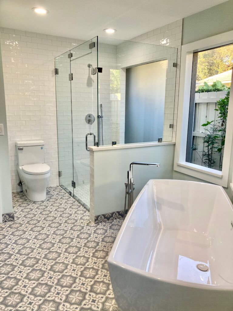 A bathroom with a tub , toilet , shower and window.