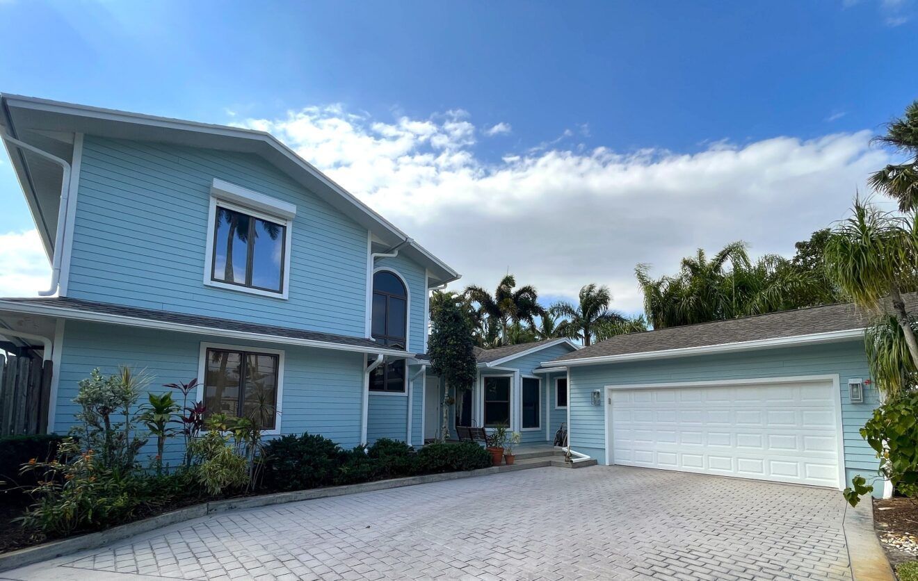 A large blue house with a garage and a driveway.