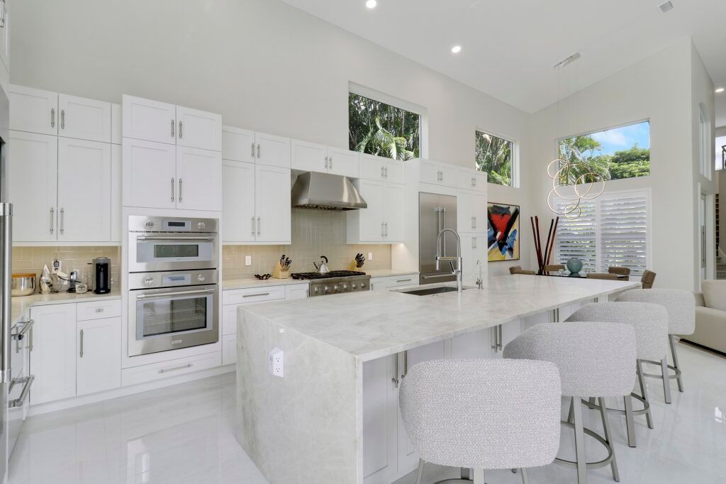 A kitchen with white cabinets , stainless steel appliances , and a large island.