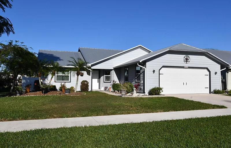 A white house with a gray roof and a white garage door