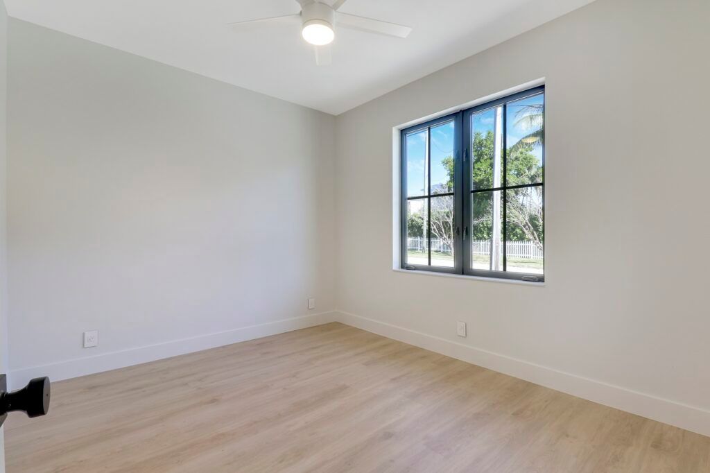 An empty bedroom with a ceiling fan and a window.