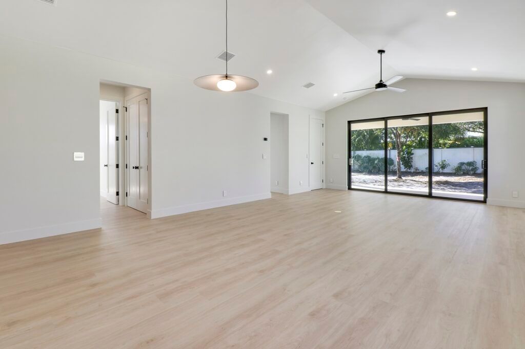 An empty living room with hardwood floors and sliding glass doors