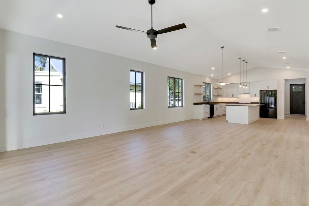 A large empty room with hardwood floors and a ceiling fan