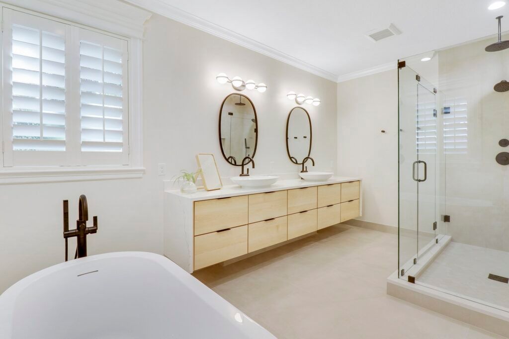 A bathroom with a bathtub , sinks , mirrors and a walk in shower.