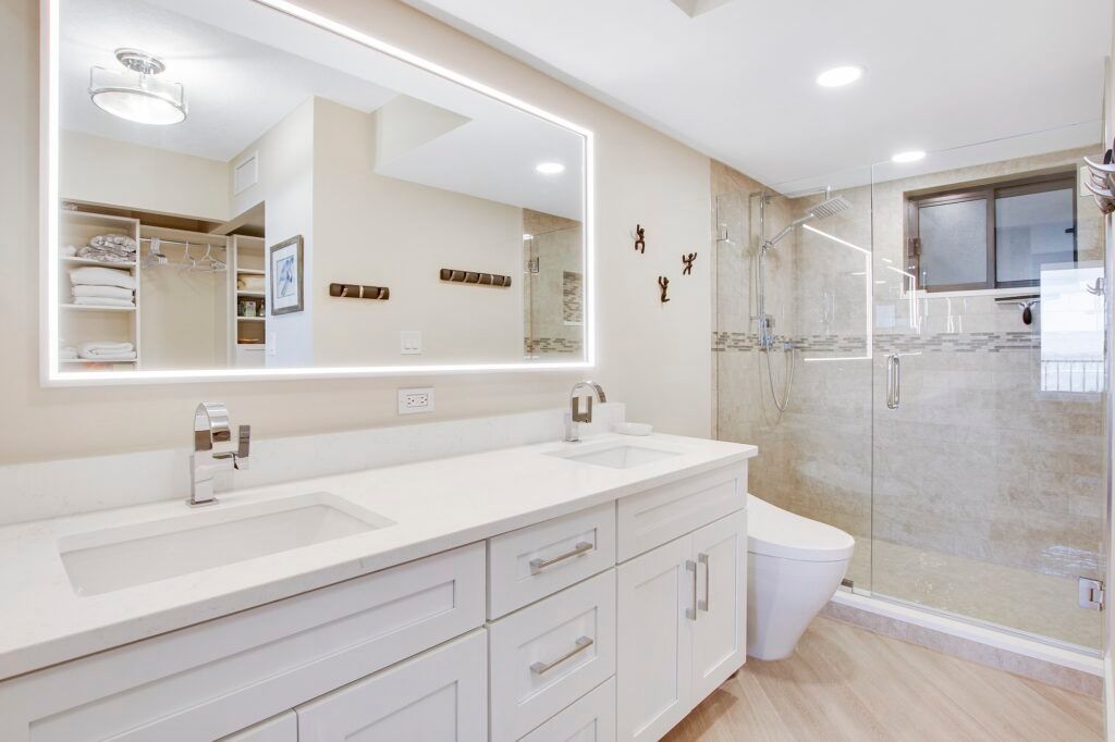 A bathroom with two sinks , a toilet , and a large mirror.