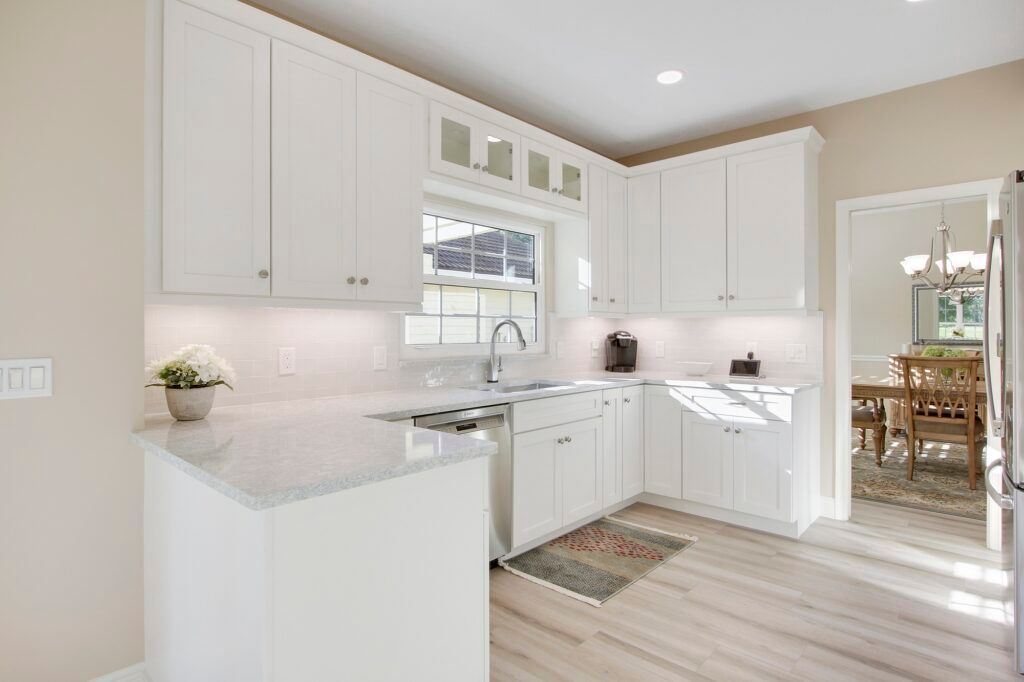 A kitchen with white cabinets , granite counter tops , a sink , and a window.