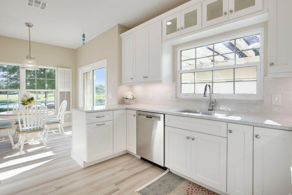 A kitchen with white cabinets and stainless steel appliances and a large window.