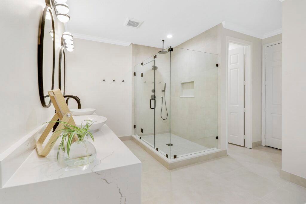 A bathroom with a walk in shower , sink and mirror.