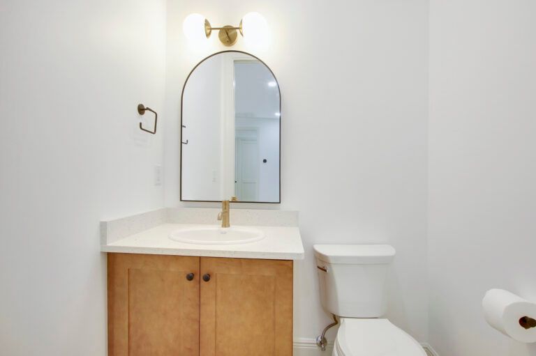 A bathroom with a sink , toilet and mirror.