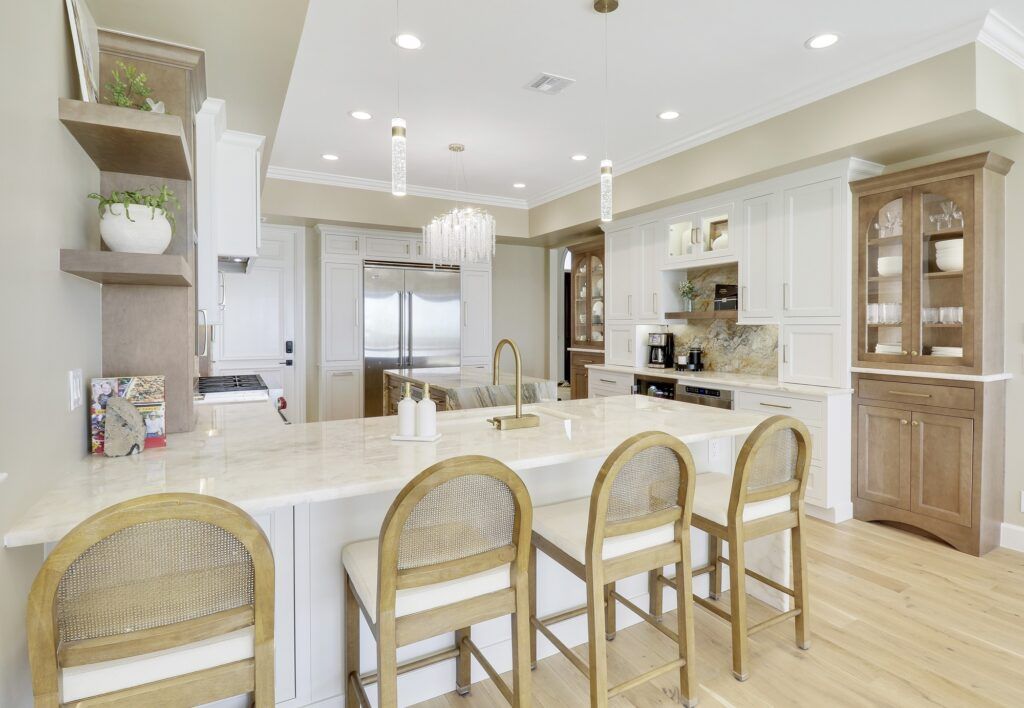 A kitchen with white cabinets , a large island , and wicker chairs.