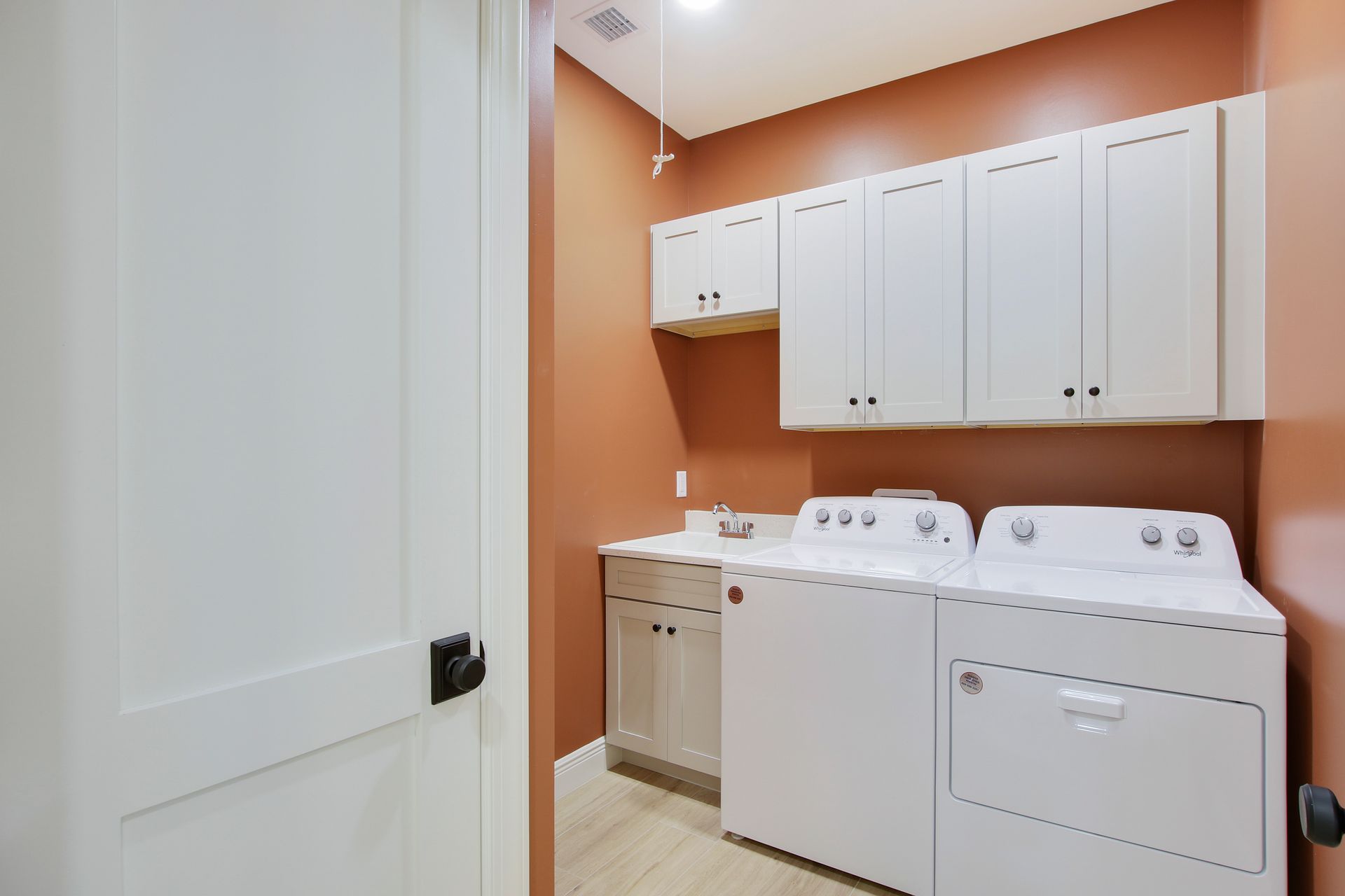 A laundry room with a washer and dryer and white cabinets.