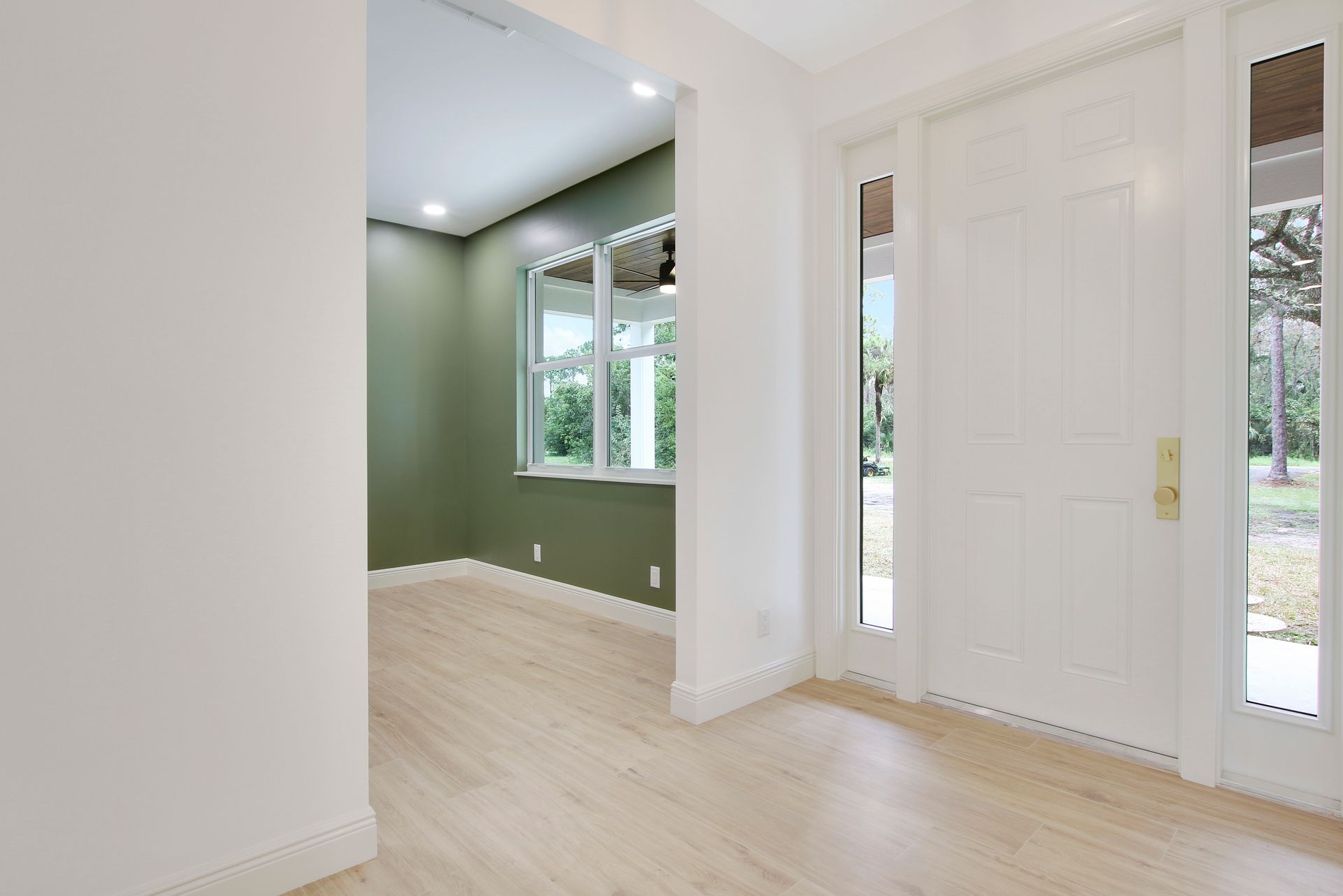 A hallway in a house with a door and a window.