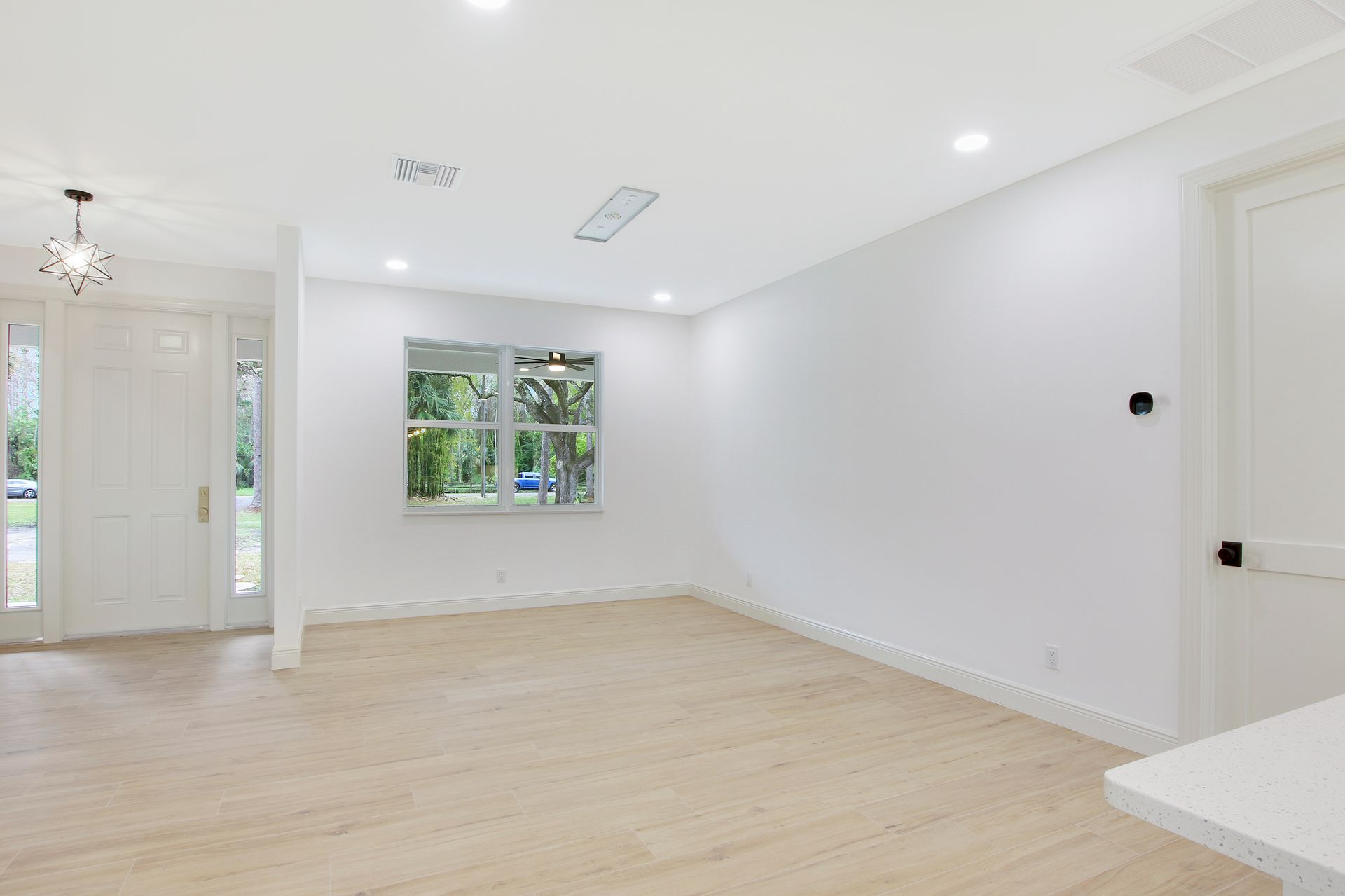 An empty living room with hardwood floors and white walls.