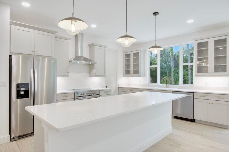A kitchen with white cabinets , stainless steel appliances , and a large island.