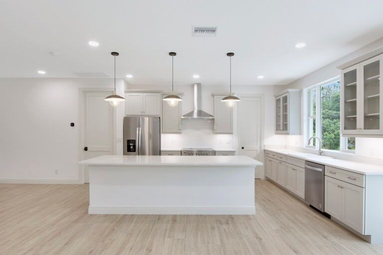 An empty kitchen with white cabinets and stainless steel appliances.